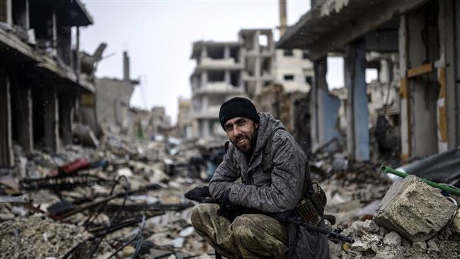A young Kurdish marksman sits in the rubble in the Syrian town of Kobani, also known as Ain al-Arab, on January 30, 2015. (AFP)