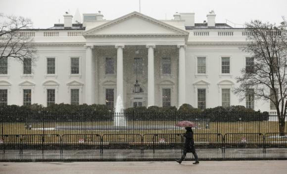 Snow starts to fall as a woman walks past the White House in Washington March 5, 2015. CREDIT: REUTERS/KEVIN LAMARQUE