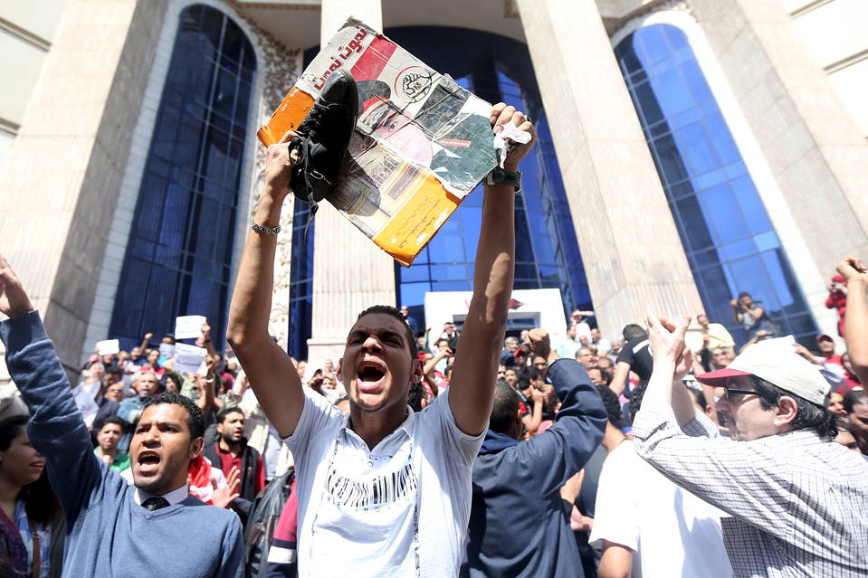 An Egyptian activist hits a poster of President Abdel Fattah Al Sisi with a shoe during a demonstration protesting the government's decision to transfer two Red Sea islands to Saudi Arabia, in front of the Press Syndicate in Cairo. PHOTO: REUTERS